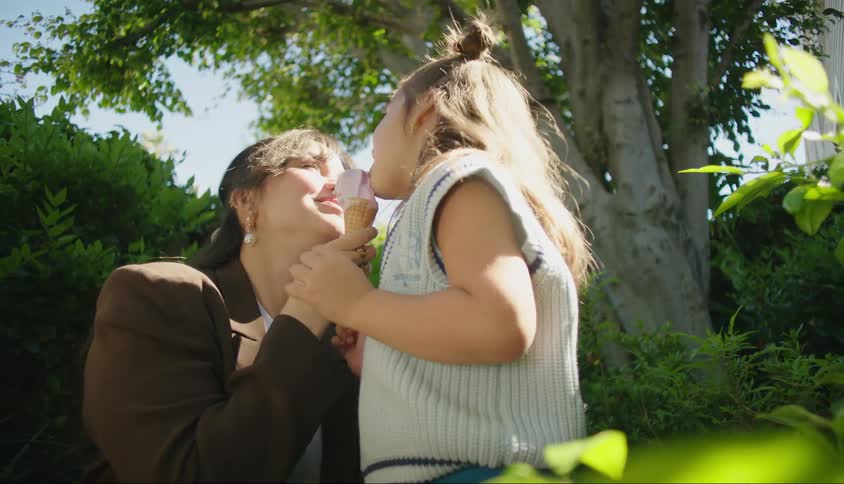 Mother and daughter sharing an ice cream in the backyard on a sunny day