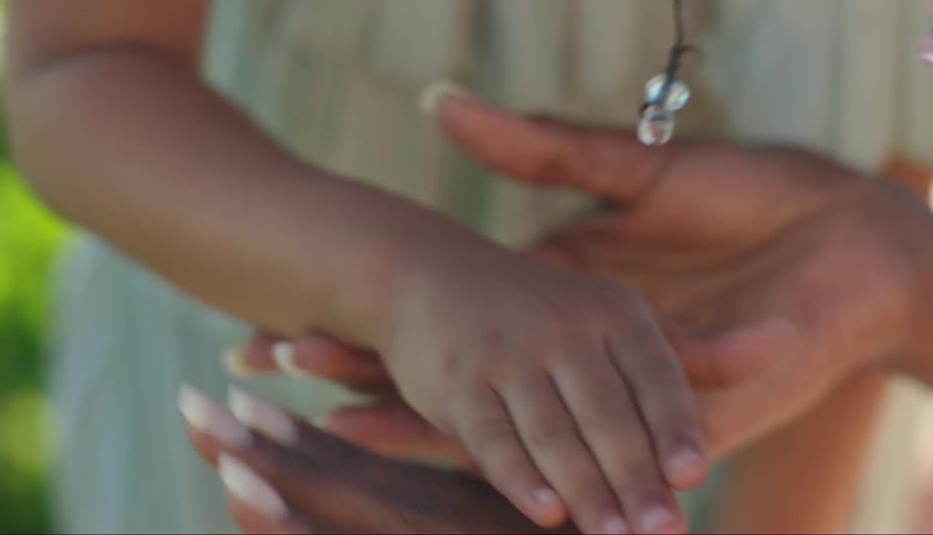 Closeup of two pairs of hands gently clasped together