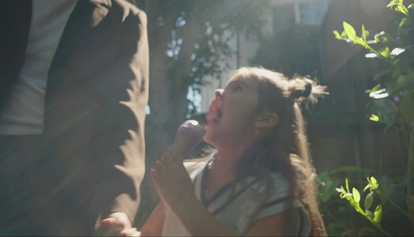 Little girl holding hands with an adult person and sucking an ice cream