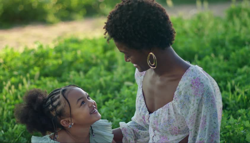 Smiling child looking at his mother while they are sitting in a garden