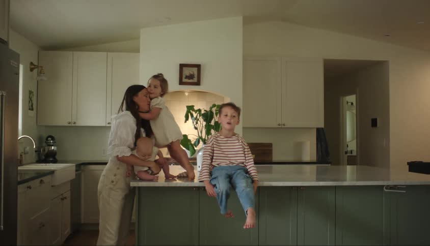 Mother with three small children in the kitchen at home