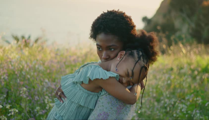 Mother giving her daughter a hug while they are in a field with flowers