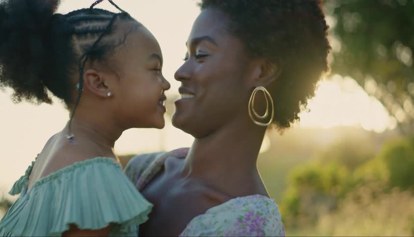 A woman smiles as she holds he affectionate daughter in her arms
