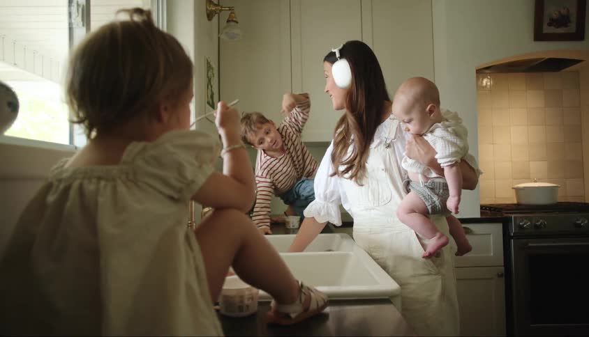 A mother talks with her children while doing the dishes