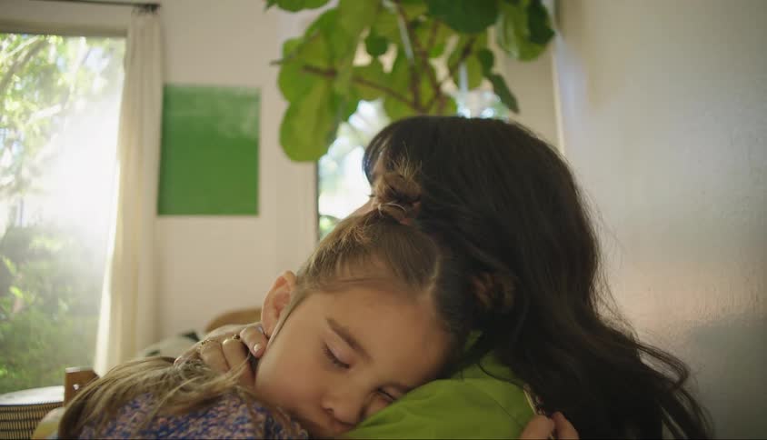 Mother and daughter hug each other in the living room near windows
