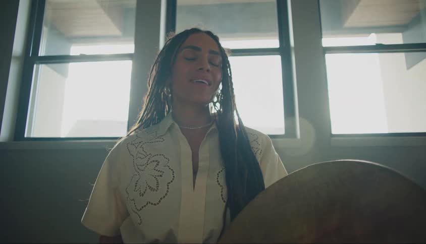 A young woman is beating a drum and singing