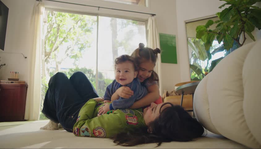 A mother plays with her two children in a room