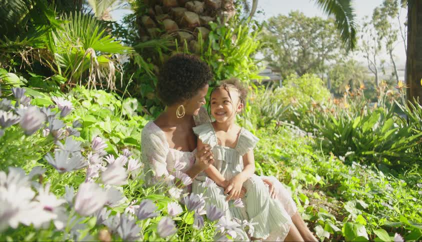 A mother and her daughter play together in a garden