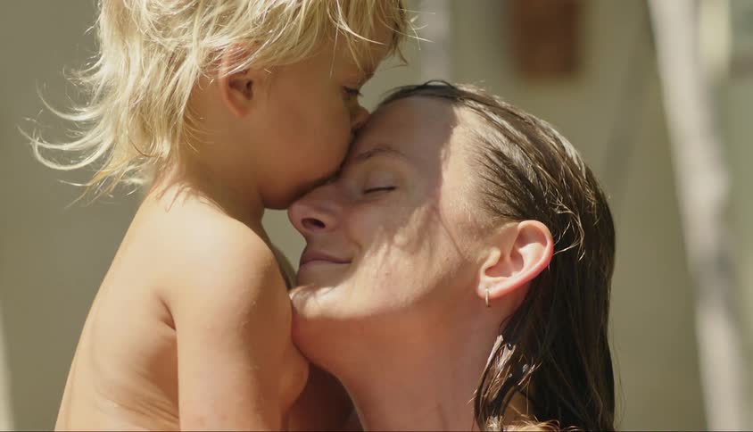 A young child hugs and kisses his mothers forehead and she smiles