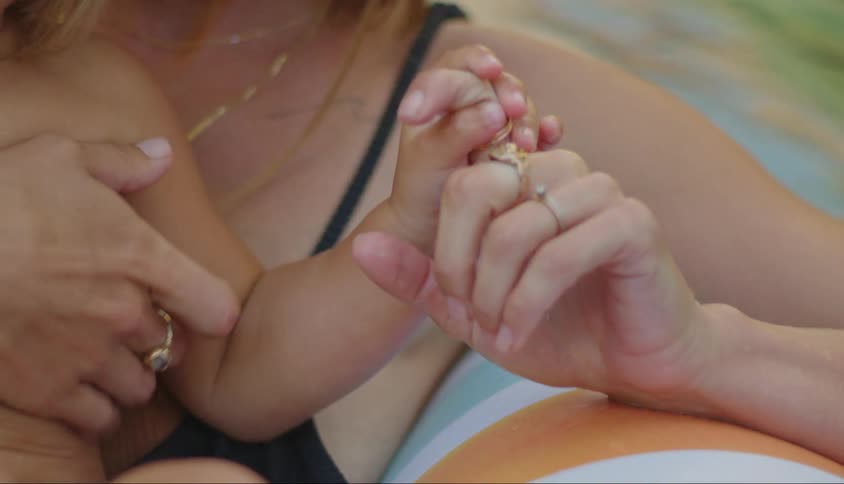 A mother and son hold hands in the pool
