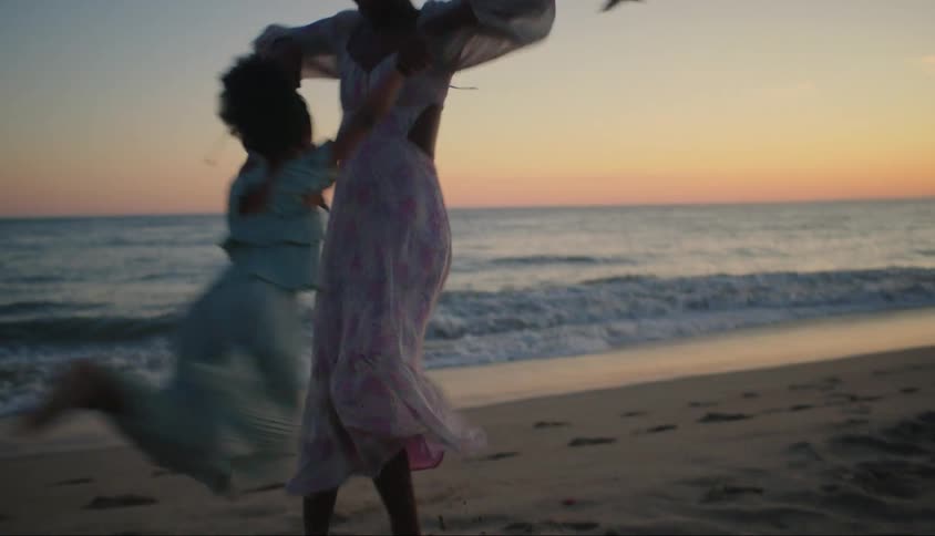 A mother swings her daughter around on the beach
