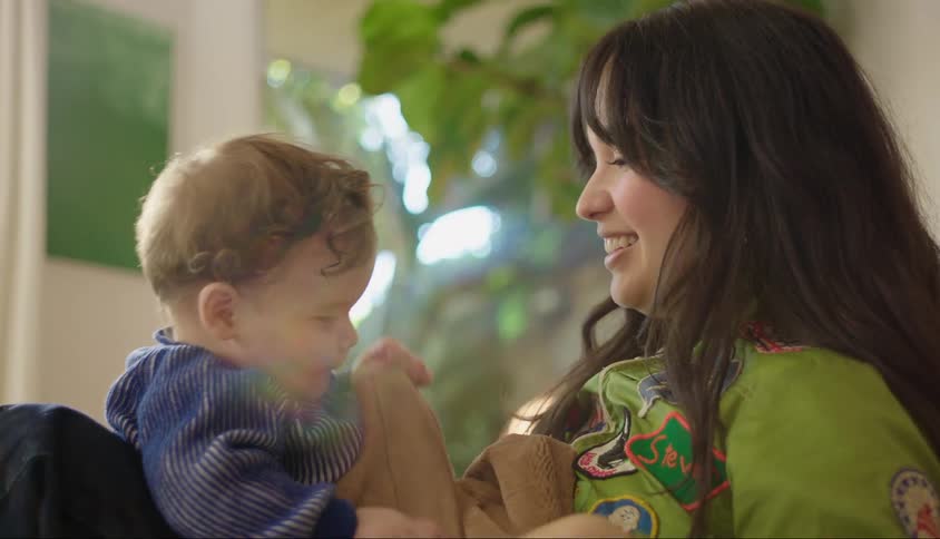 A mother plays with her infant son in a room