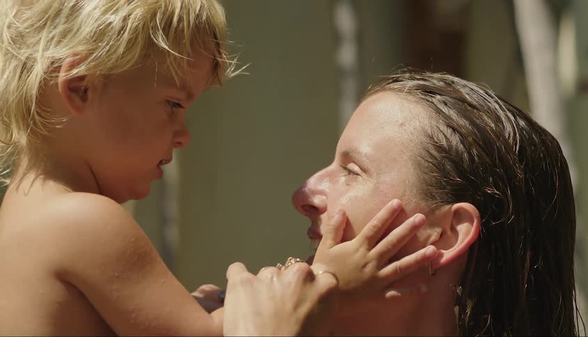 Little boy passing his hands over his mothers face