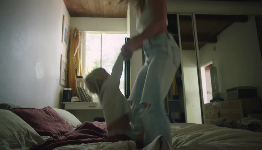 A young mother jumps on a bed with her male child