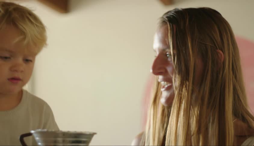 A mother helps her son with a coffee brewer