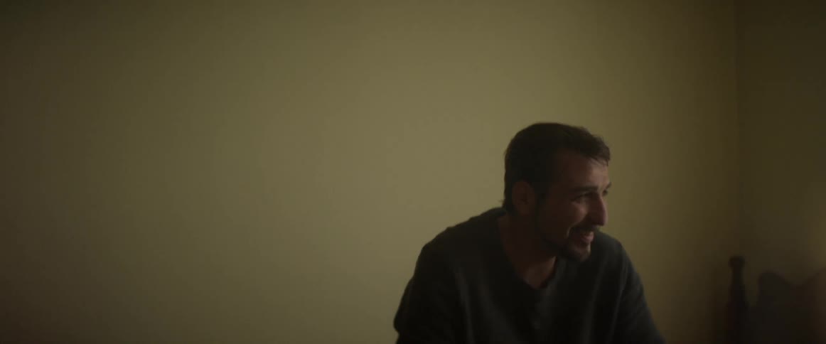 A man in a sweater holding a cup with a straw in it and smiling