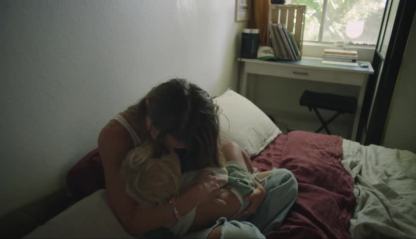 Mother giving a kiss to her daughter while sitting on the bed