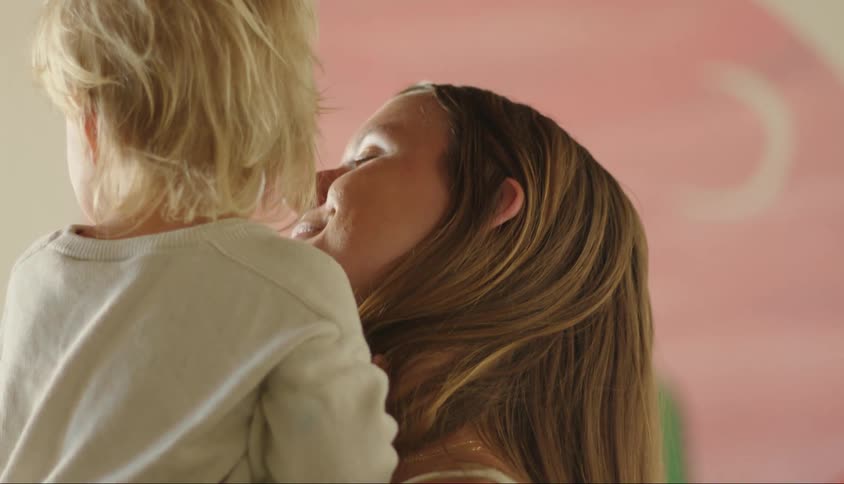Mother picking up her daughter and giving her a kiss