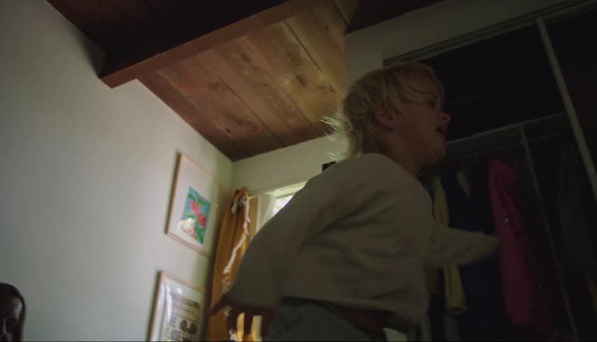 Little girl jumping on the bed and her smiling mother right behind