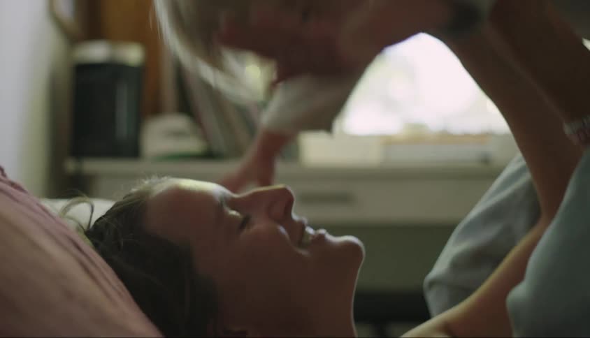 Mother lying in bed playing with her little son