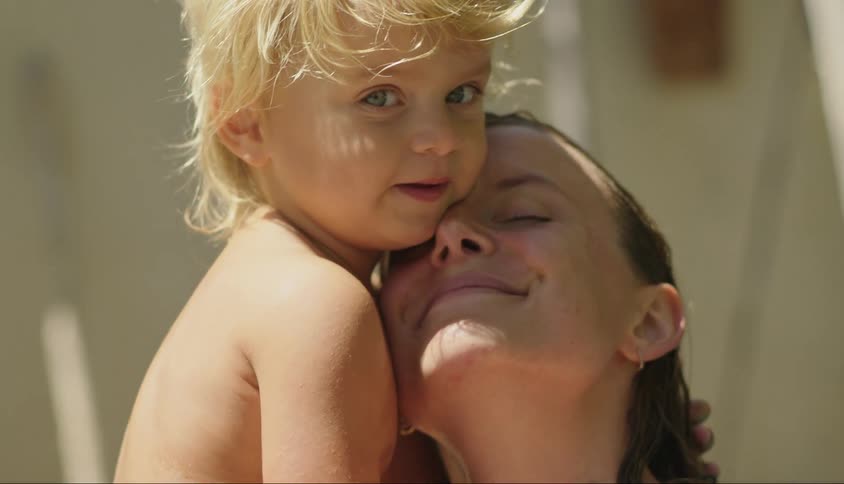 A woman holds and hugs a young child while both have big smiles on their faces