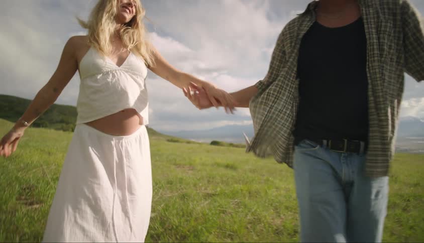 A man and a woman holding hands and walking across a field