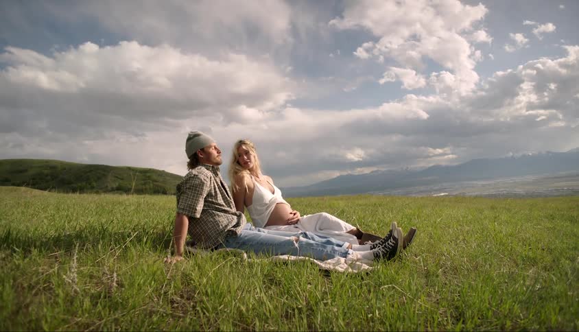 Man sitting next to a pregnant woman in an open field