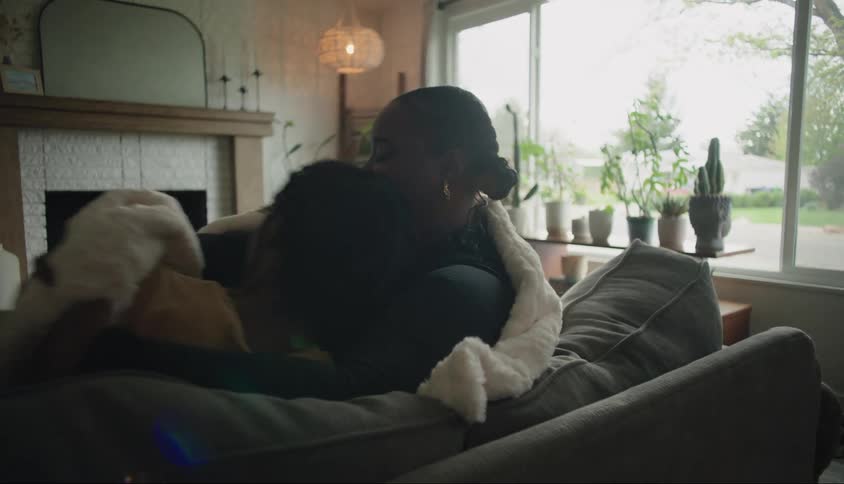 Son sitting next to his mother on the couch who covers him with a blanket