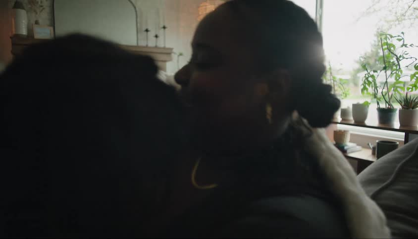 A mother embraces her son while sitting on a couch in a living room