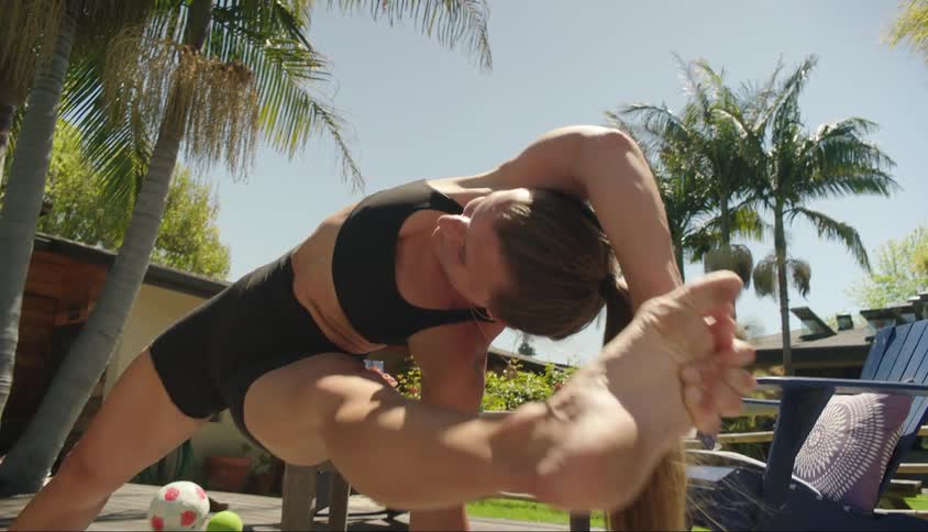 A young woman stretches on a patio outside of a house