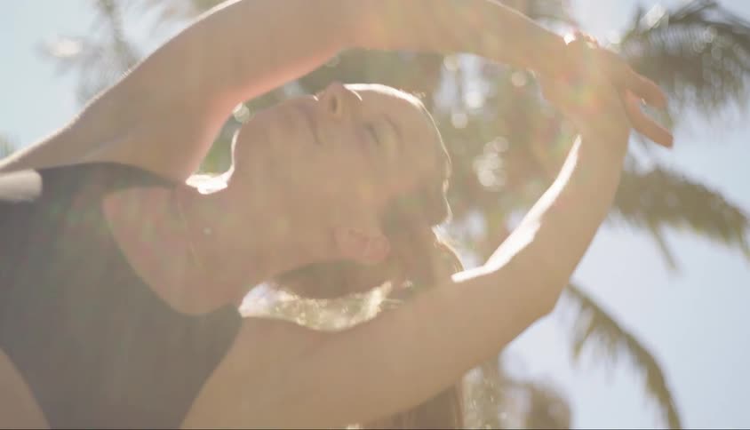 A woman is stretching under the bright sun