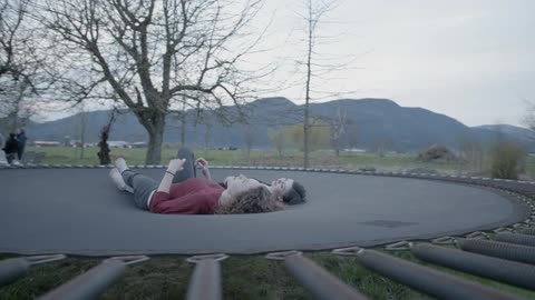 Two women lay on a trampoline during the day