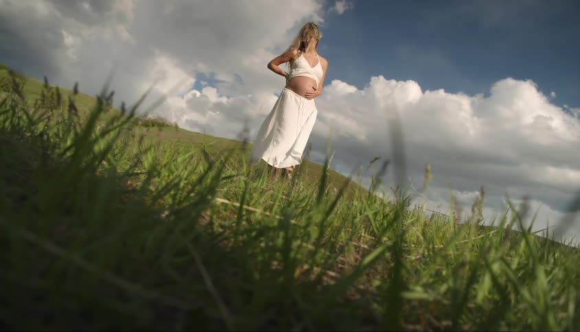 Woman in white dress walking while pregnant