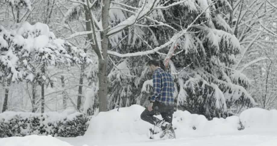 Man holding shovel walking through the snow