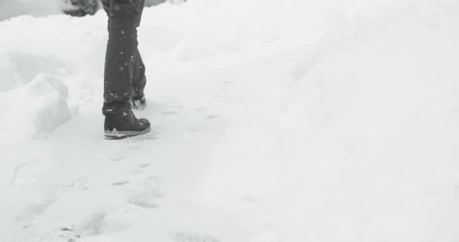 A person walks through the snow toward a building