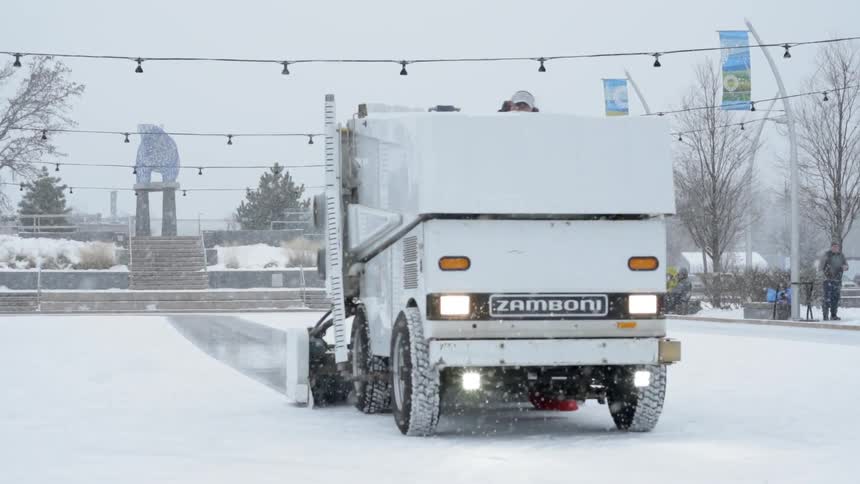 A zamboni cleans the snow off the ice
