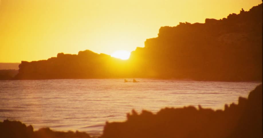 A strong orange sun glow on the horizon in front of the sea