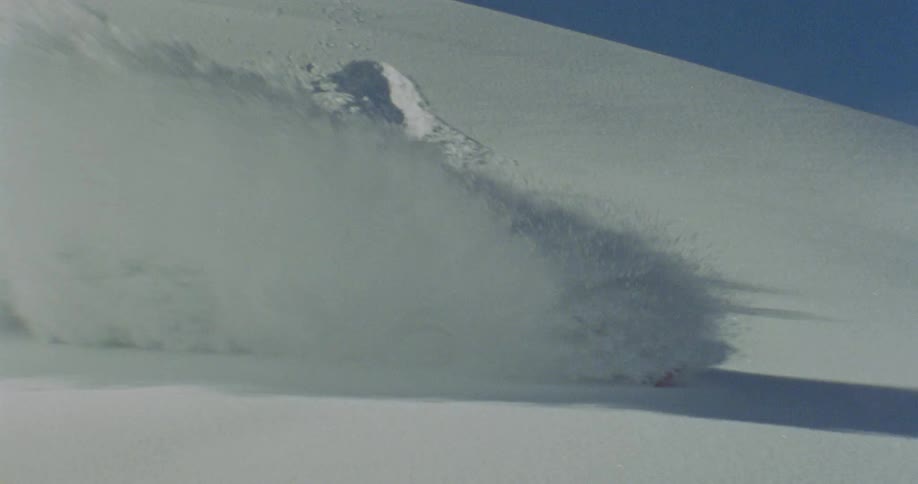 Person on a snowboard jumping on a mountain and doing tricks through the snow