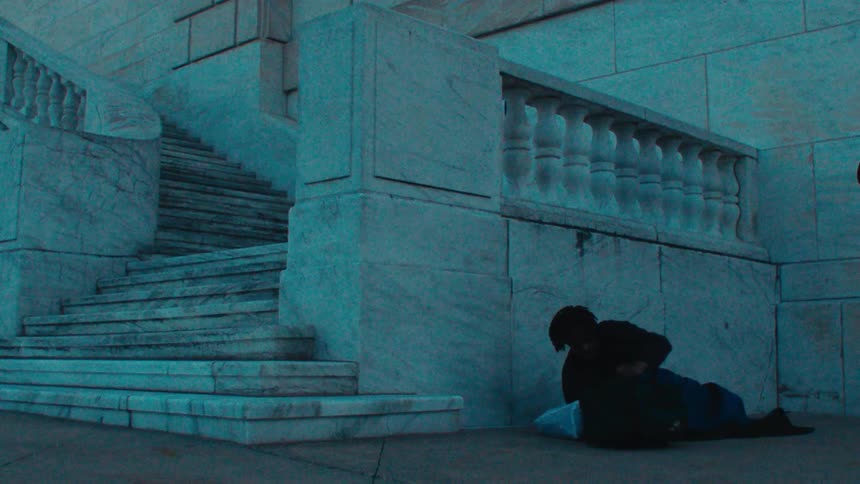 A homeless man is poked with a broom to wake up