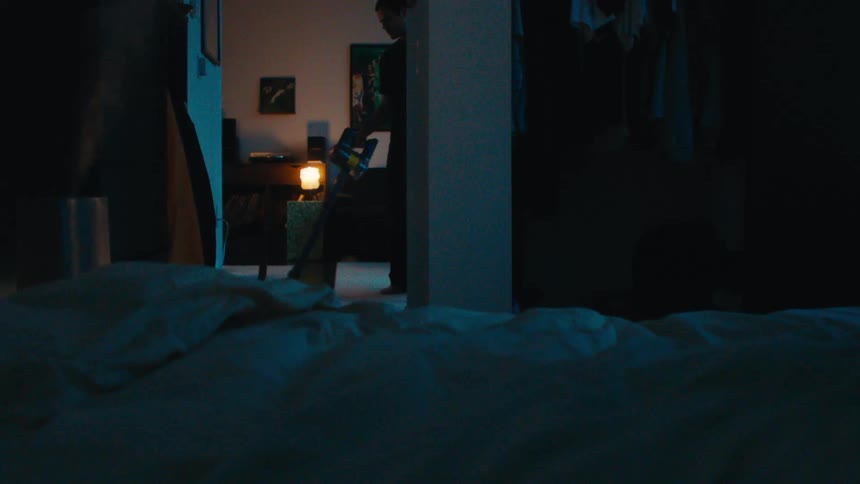 Man with a vacuum cleaner cleaning the dark house at night