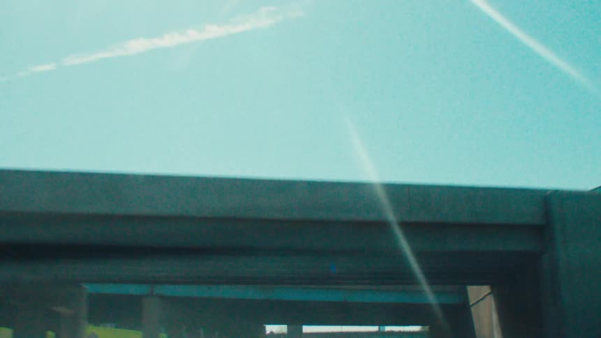View from the windshield of a car moving through a city crossing overpasses during a clear day