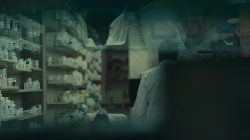 A womans face looking straight ahead in a reflective shelf and then she turns and walks
