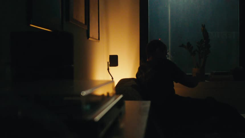 A man lights an object on fire and then sits and watches tv while smoking