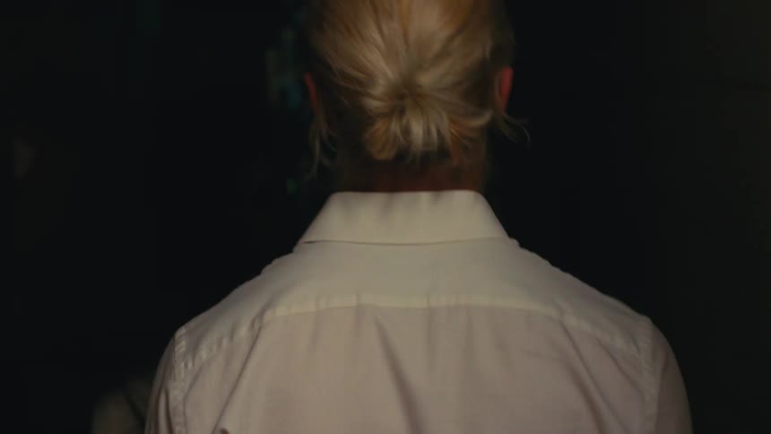The back of the head of a blond man with tied up hair who is walking on an external path to an internal location