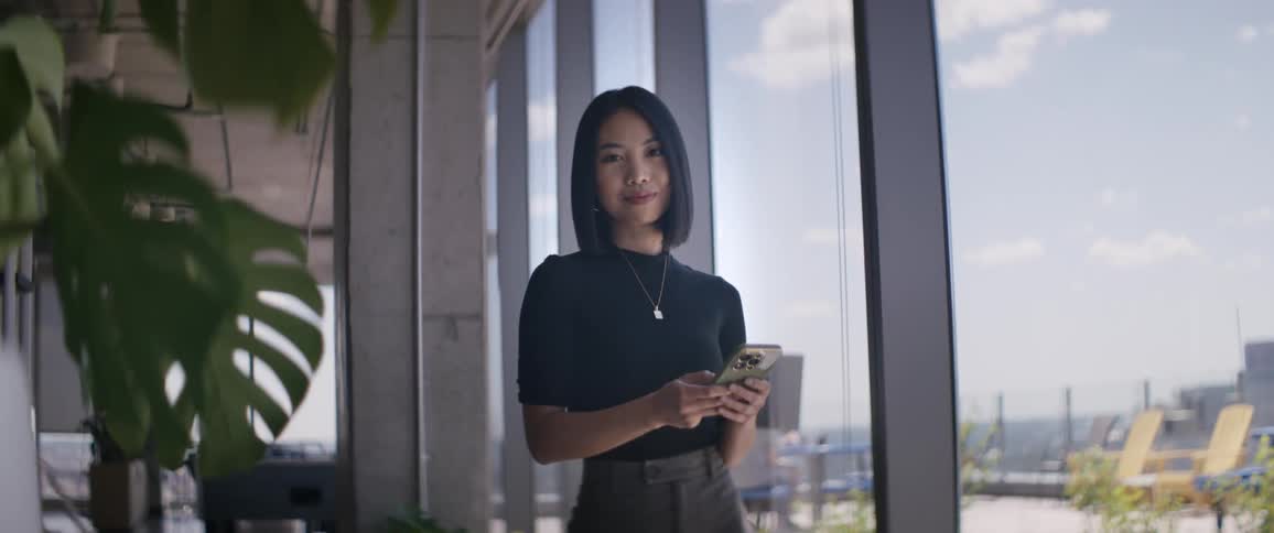 Woman with a happy facial expression using her cell phone in a work environment