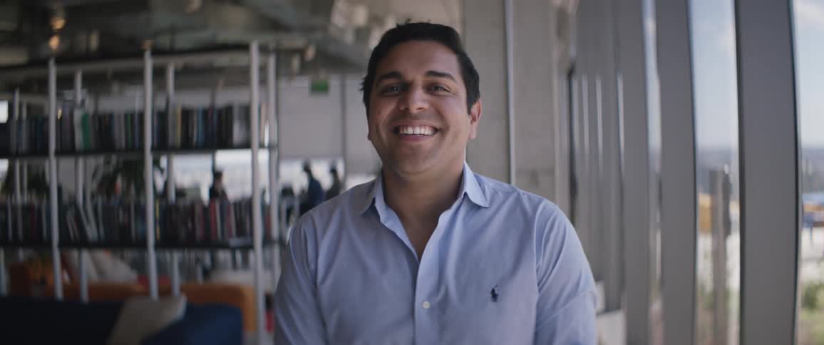 A young man laughing by the windows of a library