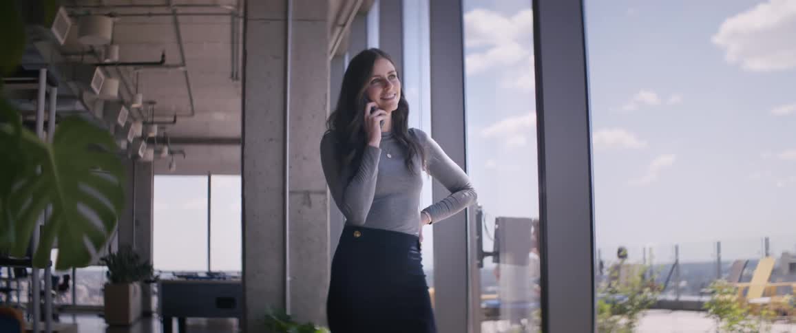 Woman in an office near the window talking on her cell phone