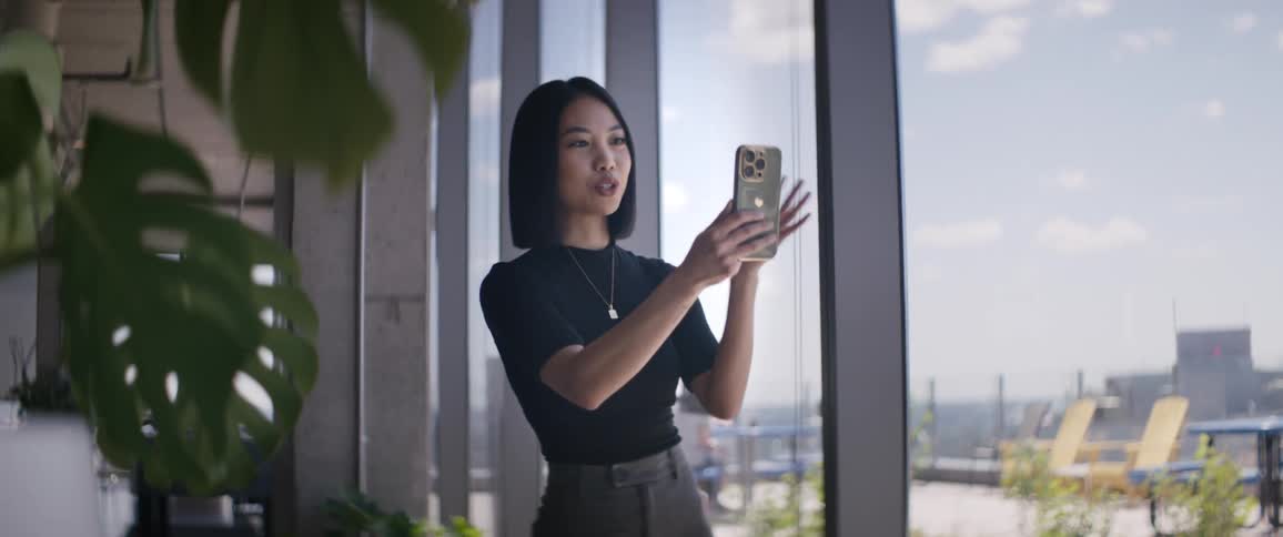 Woman inside a building next to windows talking in selfie with her cell phone