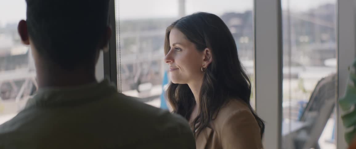 A woman talks to a man by the windows of a large building