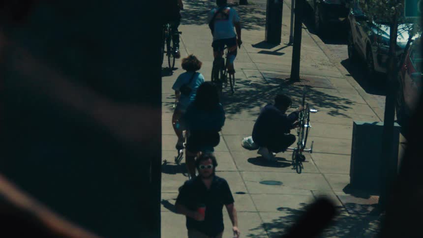 Man pedaling an exercise bike indoors and outside another man repairing a manual bike